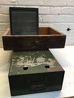 Wooden drawer atop green steel drawer with black frame inside