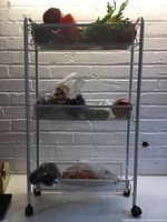 Full view of white three-tier mesh cart with faux produce on each level