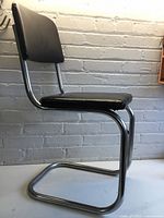 Side view of one chrome cantilever chair with black upholstery