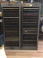 Front view of two grey metal printing galley cabinets loaded with trays