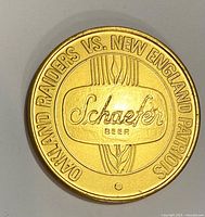 Obverse showing Oakland Raiders vs New England Patriots text and Schaefer Beer logo