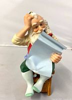 Front view of Santa figurine seated holding blueprint