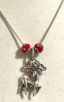 Close-up of necklace showing red beads and reindeer pendant