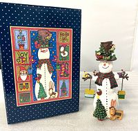 Snowman figurine beside original illustrated box, full view