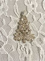 Front view of rhinestone Christmas tree brooch on lace background