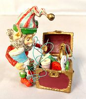 Front view of elf figurine holding thread beside open sewing chest