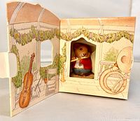 Figurine inside opened gazebo-illustrated box with visible violin and tuba art