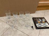 All twelve glasses, boxed coaster set and crystal stopper on tile floor