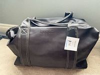 Front view of dark brown bugatti weekender duffel with tag attached