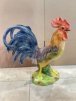 full left-side view of glazed ceramic rooster figurine on tile