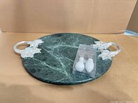 Top view of green marble round board with silver handles and two packaged spreader knives
