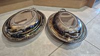 Two Viking silver-plated oval covered serving platters with lids displayed side by side