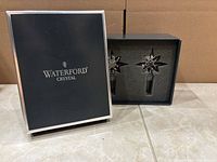 Open box displaying two crystal stoppers seated in foam insert