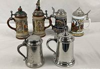 Group shot of four ceramic steins and two metal tankards