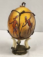 Full view showing painted ostrich egg mounted on stand