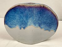Front view of flattened oval vase showing blue glaze over grey base