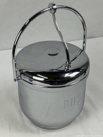 Full view of ice bucket with handle raised, showing monogram