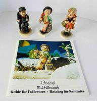 Three Hummel figurines and catalog cover