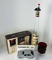 Full lot showing boxed liquor glasses, Italian liquor bottle, Peugeot model car, ruby glasses