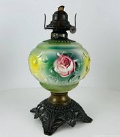 Front view of embossed glass lamp showing pink rose motif and metal burner