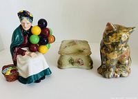Group shot of all three ceramic items: Royal Doulton figurine, floral jewellery box, camouflage cat