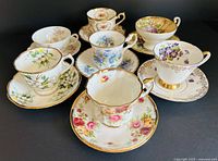 All seven teacup and saucer sets grouped, showing patterns and colours