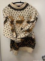 Full view of cream Fair Isle wool sweater on hanger showing overall pattern and condition