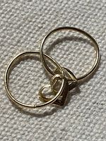 Both earrings showing hoops and heart charms on fabric background