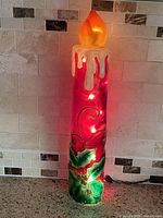 Full view of illuminated fiberglass pillar candle showing design and power cord