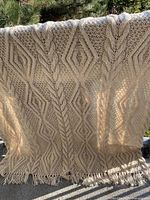 Full view of knitted afghan draped over railing showing overall pattern and fringe