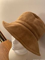 Front three-quarter view showing camel suede exterior and brim shape