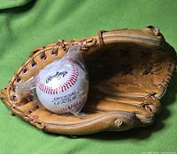 Baseball glove open with Rawlings baseball inside