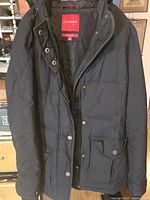Front view of black down coat hanging