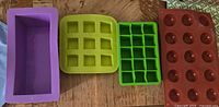 All four silicone trays laid out: loaf pan, two cube molds, half-sphere mold