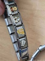 Bracelet showing Minnie, rhinestone, Belle and Olaf charms on stainless links