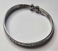 Overall view of round silver bangle showing engraved design