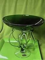 Full view of green art glass pedestal bowl on green background