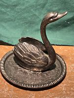 Front view of metal swan ring holder on ornate dish