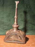 Full view of metal and glass oil lamp showing wick and ornate metalwork