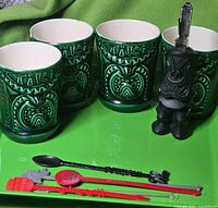 All items together on green tray: four tiki mugs, bottle opener, four stir sticks