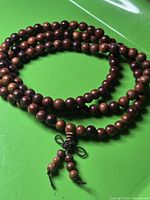 Full view of coiled wooden mala necklace showing beads and tassel