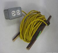 Entire extension cord wound on wood frame with outlet box visible