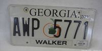 Front of Georgia license plate showing number, graphics, county, sticker