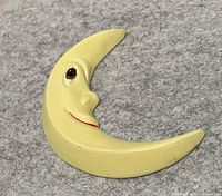 Front view of yellow ceramic crescent moon plaque showing facial detail