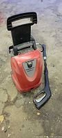 Front view of red Husky pressure washer with spray gun and wand beside