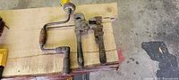 overview of two pipe wrenches and brace hand drill on workbench