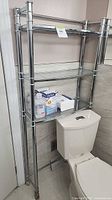 Full view of chrome over-toilet shelf showing three glass shelves and overall structure