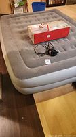 Inflated Coleman queen air mattress with pump and box on top