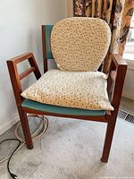 Front view of one chair with cushions showing wood frame, turquoise vinyl, beige cushions