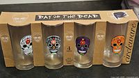 Front view of boxed four-piece Day of the Dead skull glass set